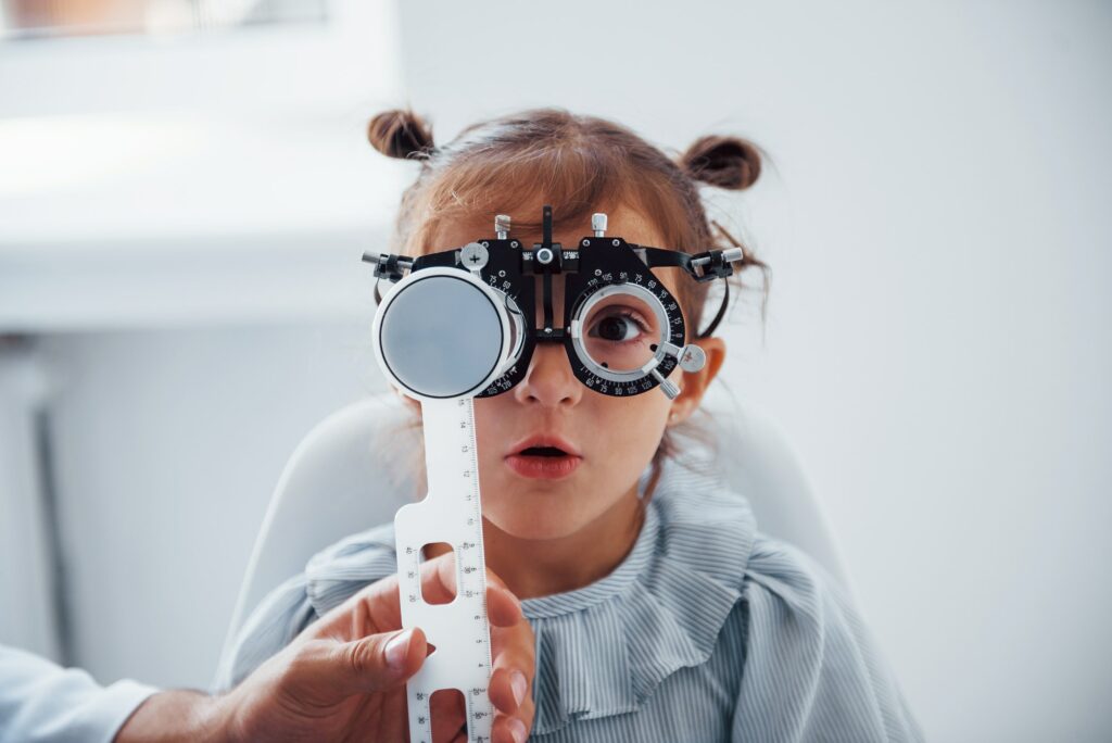 Little girl in eyewear in ophthalmology clinic have test of vision