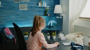 Young girl playing shoot video games on computer at desk