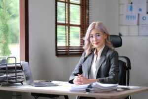Charming young Asian woman wearing glasses holding a pen notebook laptop at the office.