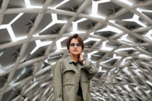 Stylish young Asian woman wearing eyeglasses and casual wear posing against geometric architectural