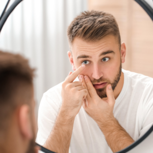 Man in a white shirt looking into a mirror while adjusting his contact lens near his eye (close-up)